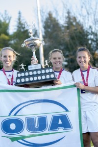 Captains Emily Brown, Kelsey Tikka and Emily Brown hold the championship trophy and banner. (Photo by Heather Davidson)